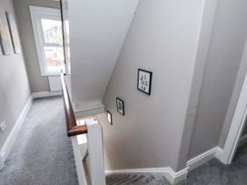 A staircase in a hallway with framed pictures at Tennyson House Scarborough