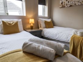 A bedroom with two beds and a bedside lamp at Tennyson House in Scarborough