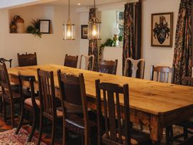 A dining room with a long table and chairs at Cwmalis Hall Llangollen