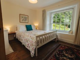 A bedroom with a bed and a window overlooking greenery at Cwmalis Hall Llangollen
