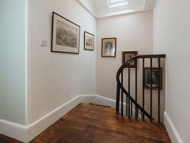 A staircase with framed artwork on walls at Cwmalis Hall in Llangollen