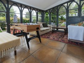 A conservatory with a foosball table and seating area at Cwmalis Hall in Llangollen