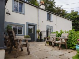 An outdoor seating area with wooden chairs and a table at Cwmalis Hall in Llangollen