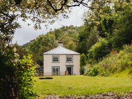 A house surrounded by grass and trees at Cwmalis Hall in Llangollen