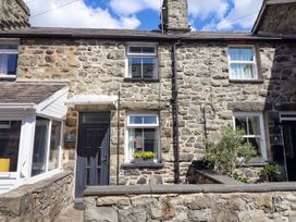 Stone facade of a two-story house with a black door and two white-framed windows with flower boxes at 6 Smithfield Lane in Dolgellau