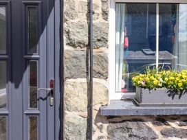 A stone wall with a gray door and a window with a flower box containing yellow flowers at 6 Smithfield Lane Dolgellau