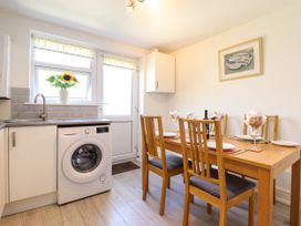 A kitchen dining area with a wooden table set for six people and a washing machine under a countertop at 6 Smithfield Lane in Dolgellau