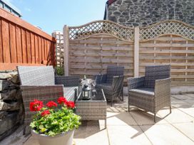 A patio area with grey wicker furniture and a flower pot with red flowers at 6 Smithfield Lane in Dolgellau
