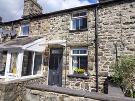 Stone exterior of a house with a black door and two windows with flower box at 6 Smithfield Lane in Dolgellau