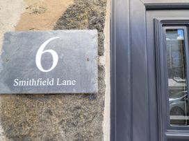 A door with a stone wall and a house number plaque reading 6 Smithfield Lane at 6 Smithfield Lane in Dolgellau