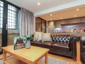 A living room with a sofa, table, and kitchen area at Tornado @ Engine Shed in Whitby