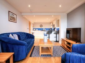 A living room with a sofa, coffee table, and kitchen area at Blue Peter @ Engine Shed Whitby