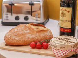 A kitchen countertop with bread, cheese, tomatoes, and a wine bottle at Evening Star @ Engine Shed in Whitby