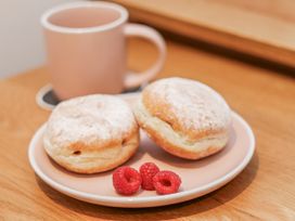 A plate with doughnuts and raspberries next to a cup at George Stephenson @ Engine Shed in Whitby