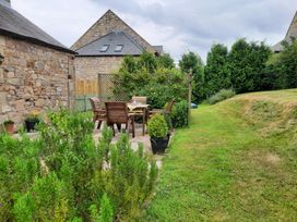 A garden with seating area and greenery at Hemmel Cottage in Chatton