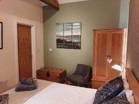 A bedroom with a bed and armchair at Hemmel Cottage in Chatton