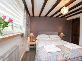 A bedroom with a bed, lamp, nightstand and flowers at Mill House in Robin Hood's Bay