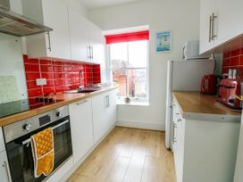 A kitchen with white cabinets red tiles and wooden countertops at Llewelyn House in Llandudno