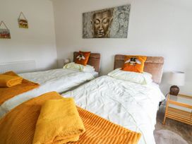 A bedroom with two single beds with white bedding and orange bee pillows at Llewelyn House in Llandudno