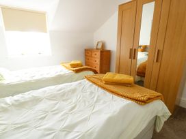 A bedroom with two single beds white bedding wooden wardrobe with mirror and chest of drawers at Llewelyn House in Llandudno