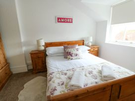 A bedroom with a wooden bed with pillows and folded towels a window and bedside tables with lamps at Llewelyn House in Llandudno