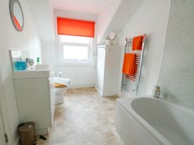 A bathroom with a bathtub a sink a toilet and orange towels at Llewelyn House in Llandudno