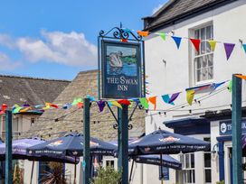 A sign for The Swan Inn with flags and patio umbrellas at Meadow View Cottage in Lympstone