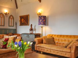 A living room with sofas and a vase on a table at Lazy Hare at Jen's Orchard St Giles On The Heath