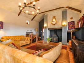 A living room with a sofa and a fireplace at Lazy Hare at Jen's Orchard St Giles On The Heath