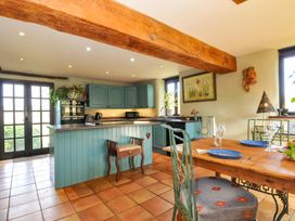 A kitchen with dining area and blue cabinets at Lazy Hare at Jen's Orchard in St Giles On The Heath