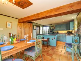 A dining area with a table and kitchen in Lazy Hare at Jen's Orchard St Giles On The Heath
