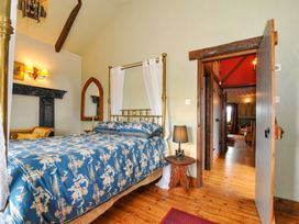 A bedroom with a bed and mirror at Lazy Hare at Jen's Orchard St Giles On The Heath