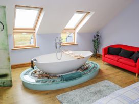 A bathroom with a bathtub and sofa at Ocean Sail House Termon near Dungloe County Donegal