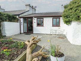 An outdoor area with a house and table with chairs at Bwthyn in Moelfre