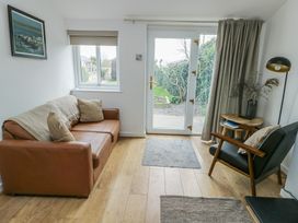 A living room with a sofa and door leading to the garden at Bwthyn in Moelfre
