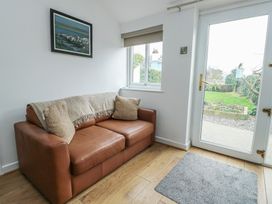 A snug with a sofa and a door leading outside at Bwthyn in Moelfre