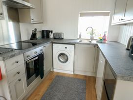 A kitchen with appliances and a washing machine at Bwthyn in Moelfre