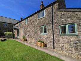 An outdoor view of a stone house with flower beds at Dale Barton in Wells