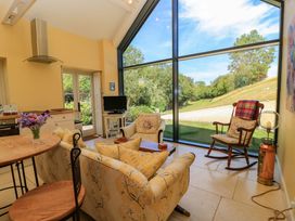 A living room with a large window and seating at Pheasant Cottage in Priston Village, BATH