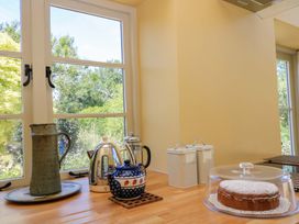 A kitchen with a cake on a stand and tea set at Pheasant Cottage in Priston Village, BATH