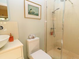 A bathroom with a shower, sink, toilet, and a painting at Pheasant Cottage in Priston Village, BATH