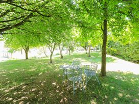 A table and chairs under trees in a garden at Pheasant Cottage in Priston Village, BATH