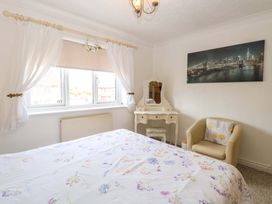A bedroom with a bed and a dressing table at Breydon Cottage in Bradwell near Gorleston-On-Sea