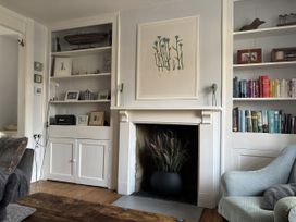 A living room with a bookshelf, fireplace, and armchair at Brock Cottage West Bay