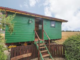 A green wooden wagon with stairs and an open door next to a wooden fence and a field at Wayside Cottage in Pocklington