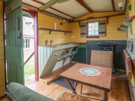 A small rustic kitchen with a wooden table and chairs a double sink and an open green door at Wayside Cottage in Pocklington