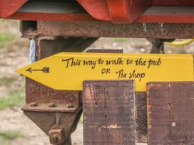 A yellow wooden sign with black writing pointing left attached to a rusty metal structure at Wayside Cottage in Pocklington