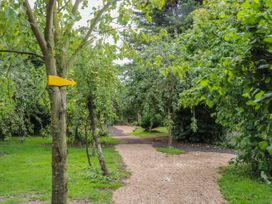A garden path with trees and a yellow arrow sign attached to a tree at Wayside Cottage in Pocklington