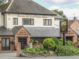Exterior view of a building with signs for a restaurant hotel public house and Mr Chu Chinese restaurant surrounded by greenery