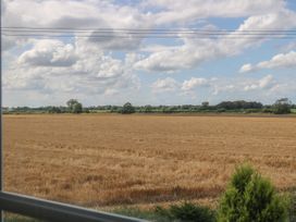 A view of a harvested field with trees and cloudy sky through a window at Wayside Cottage in Pocklington